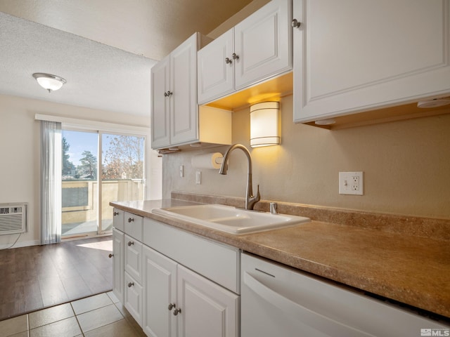 kitchen featuring white cabinets, white dishwasher, sink, light hardwood / wood-style flooring, and a textured ceiling