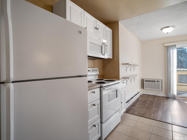 kitchen with white cabinetry, an AC wall unit, a textured ceiling, white appliances, and light wood-type flooring