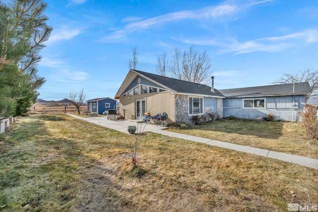 view of front of house featuring a storage unit, a patio, and a front lawn