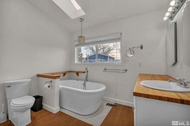 bathroom featuring hardwood / wood-style flooring, vanity, toilet, and a tub to relax in