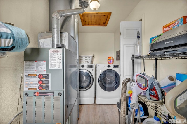 washroom featuring heating unit, light wood-type flooring, and washing machine and clothes dryer