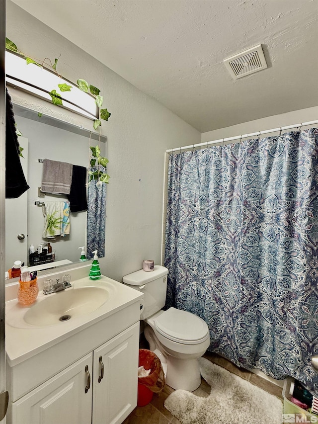 bathroom featuring a textured ceiling, vanity, and toilet