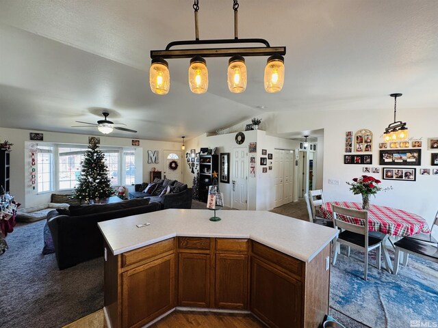 kitchen with pendant lighting, ceiling fan, a kitchen island, and vaulted ceiling