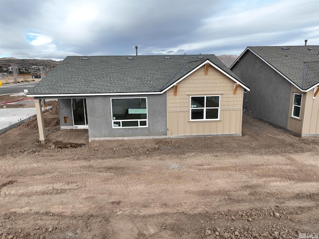 back of house featuring a shingled roof