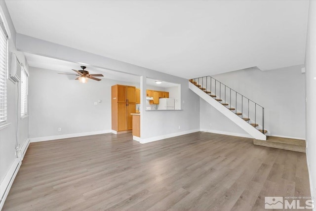 unfurnished living room featuring light hardwood / wood-style floors, ceiling fan, and a baseboard heating unit