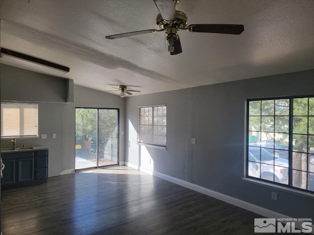 unfurnished living room featuring a textured ceiling, a wealth of natural light, dark wood-type flooring, and vaulted ceiling