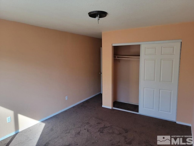 unfurnished bedroom featuring dark carpet and a closet