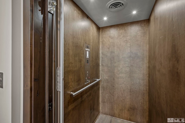 details featuring hardwood / wood-style flooring, wooden walls, and elevator