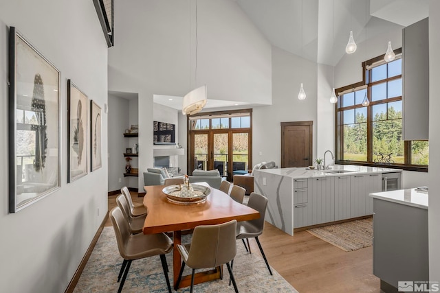 dining space with a towering ceiling, light hardwood / wood-style floors, and sink