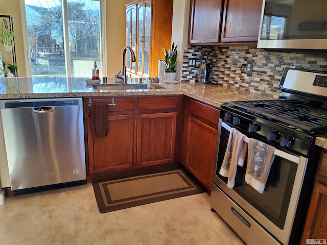 kitchen featuring a wealth of natural light, light stone counters, sink, and appliances with stainless steel finishes