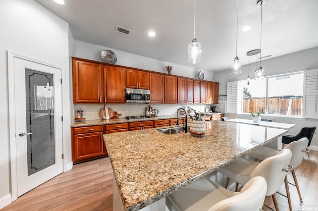 kitchen featuring light wood-type flooring, stainless steel appliances, hanging light fixtures, and sink