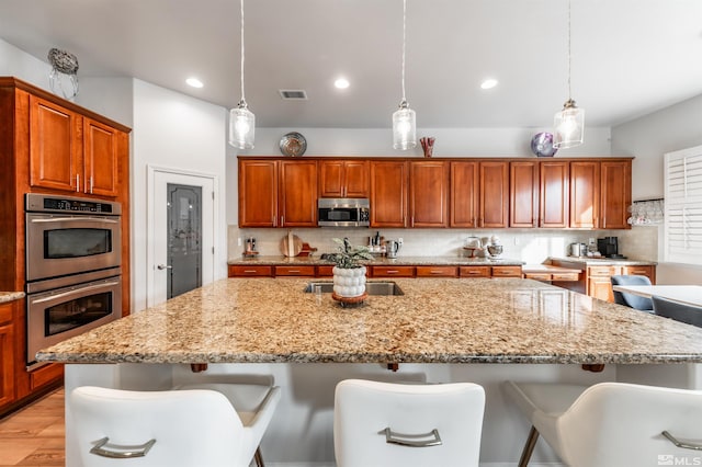 kitchen featuring pendant lighting, an island with sink, and stainless steel appliances