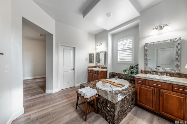 bathroom featuring vanity, wood-type flooring, and tiled bath