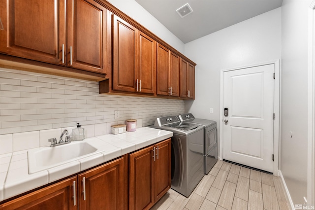 laundry area with cabinets, independent washer and dryer, and sink