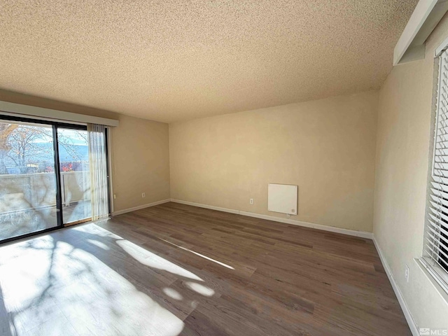 empty room with a textured ceiling and dark wood-type flooring