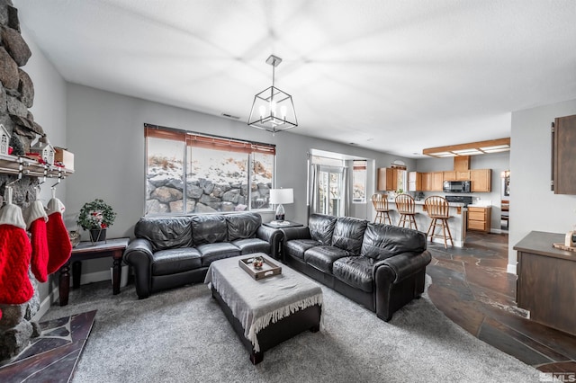 living room with stone tile flooring, visible vents, baseboards, and an inviting chandelier