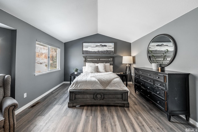 bedroom with vaulted ceiling, visible vents, dark wood finished floors, and baseboards