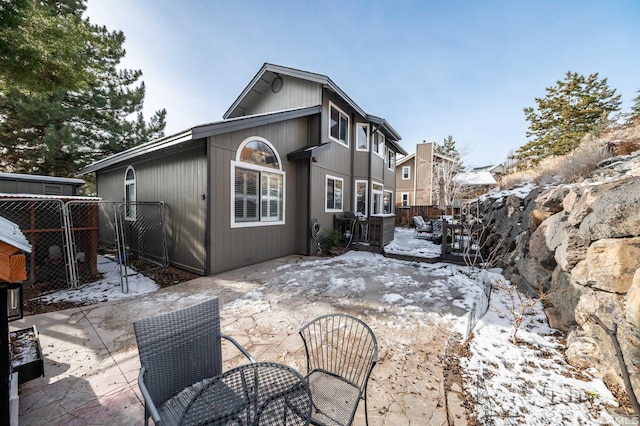 snow covered house featuring fence and a patio