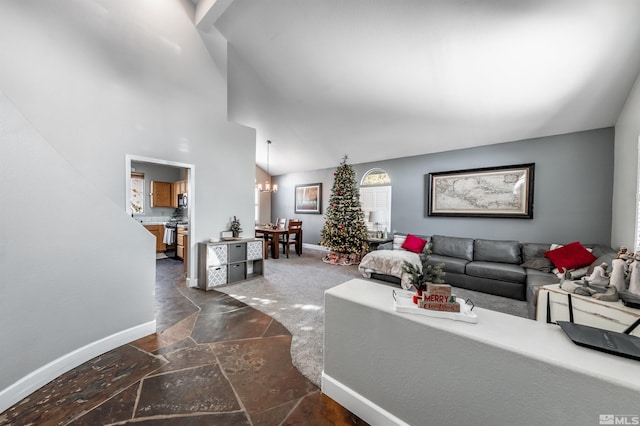 living area featuring a notable chandelier, high vaulted ceiling, stone tile flooring, and baseboards