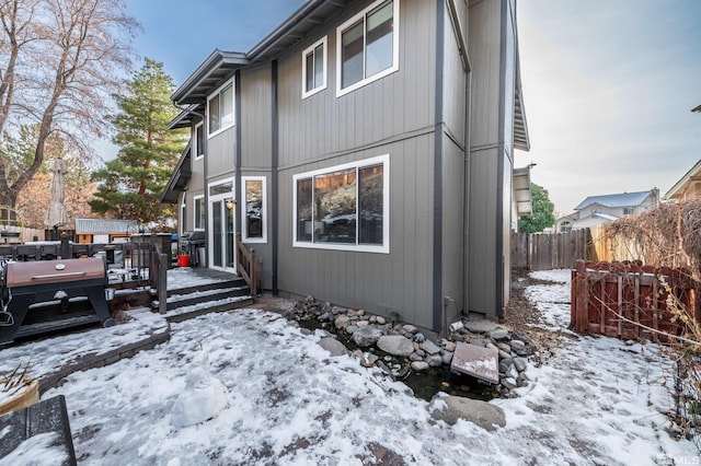 snow covered rear of property featuring fence and a deck