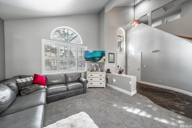 living area with a high ceiling, stone tile flooring, and baseboards