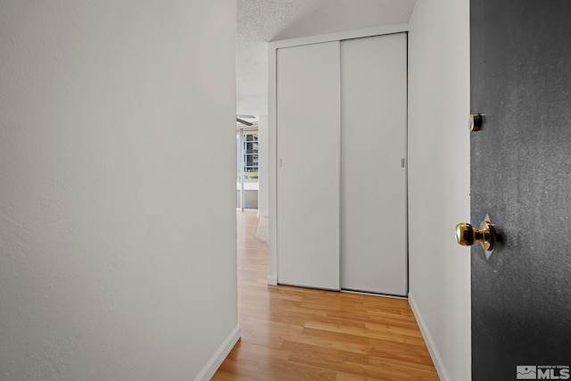 hall featuring a textured ceiling and light hardwood / wood-style flooring