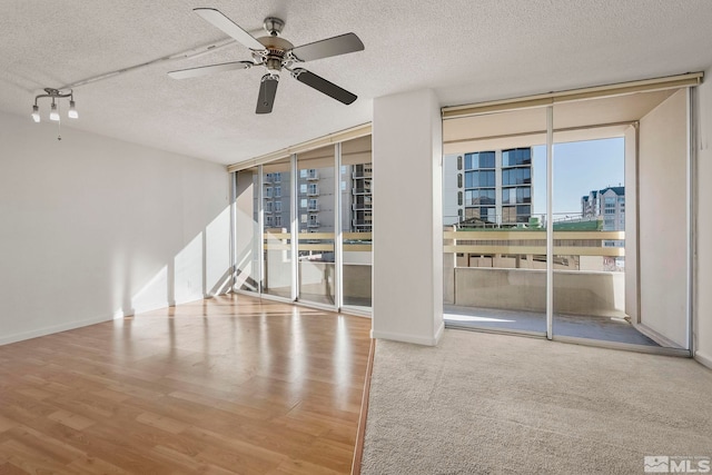 unfurnished room with floor to ceiling windows, ceiling fan, a textured ceiling, and hardwood / wood-style flooring