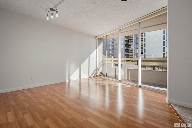 empty room featuring hardwood / wood-style floors, a textured ceiling, and expansive windows