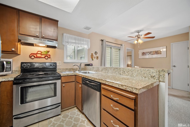 kitchen with ceiling fan, sink, stainless steel appliances, kitchen peninsula, and light carpet