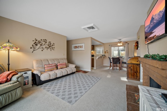 carpeted living room with ceiling fan and a brick fireplace