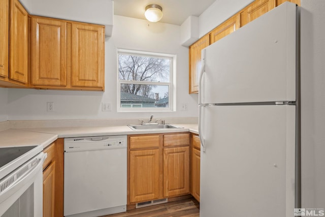 kitchen with white appliances, hardwood / wood-style flooring, and sink