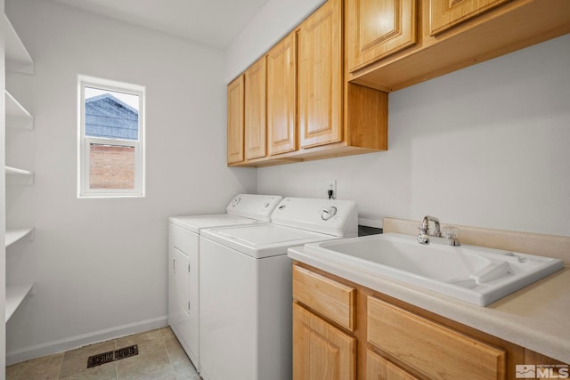 laundry room with washer and clothes dryer, light tile patterned flooring, cabinets, and sink