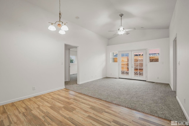 unfurnished room with french doors, ceiling fan with notable chandelier, high vaulted ceiling, and light hardwood / wood-style flooring