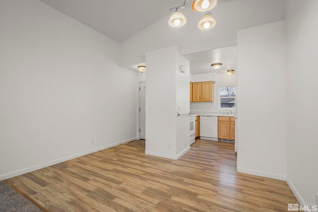 kitchen with white dishwasher, vaulted ceiling, light brown cabinets, and light hardwood / wood-style flooring