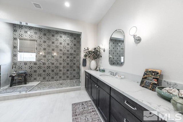 bathroom featuring vanity, a shower, and vaulted ceiling