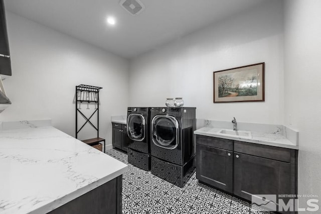 clothes washing area featuring washer and dryer, cabinets, and sink