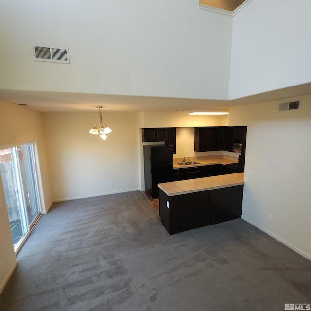 kitchen featuring dark colored carpet, a notable chandelier, and sink