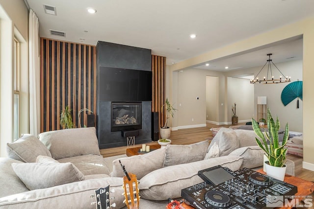 living room with wood-type flooring, a large fireplace, and an inviting chandelier