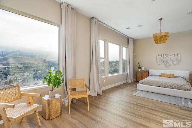 bedroom featuring a mountain view, light wood-type flooring, and multiple windows