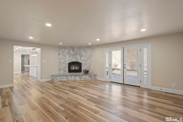 unfurnished living room featuring a fireplace, a textured ceiling, and light wood-type flooring