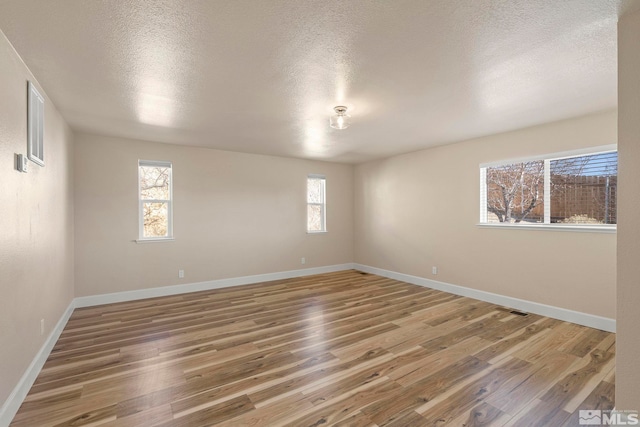 spare room with hardwood / wood-style flooring, a textured ceiling, and a wealth of natural light