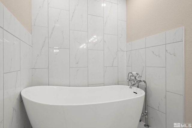 bathroom featuring a washtub and tile walls