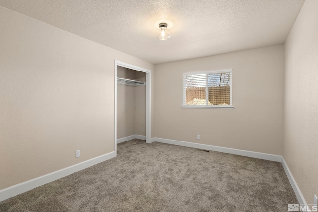 unfurnished bedroom with a closet, carpet, and a textured ceiling