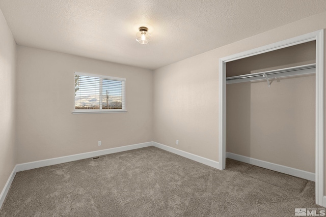 unfurnished bedroom featuring carpet flooring, a textured ceiling, and a closet