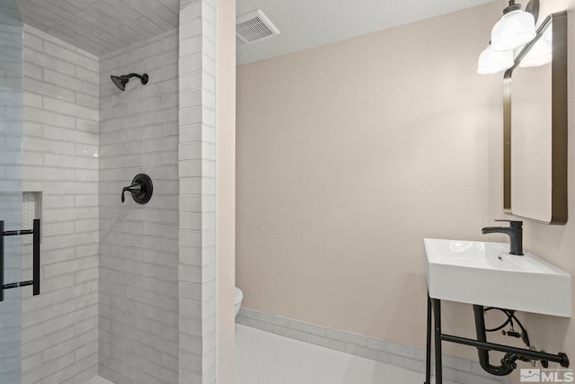 bathroom featuring a tile shower and toilet