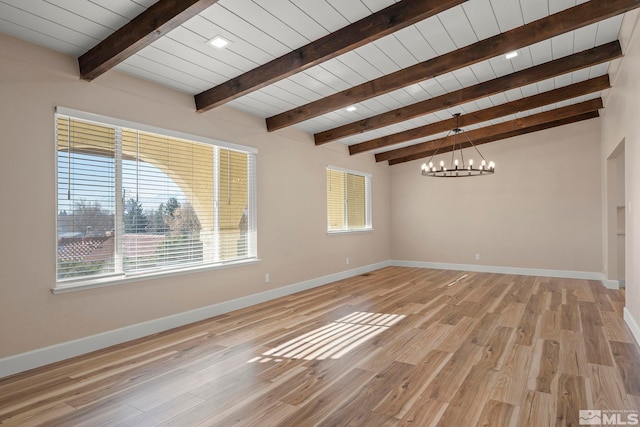 spare room featuring a healthy amount of sunlight, an inviting chandelier, and light hardwood / wood-style flooring