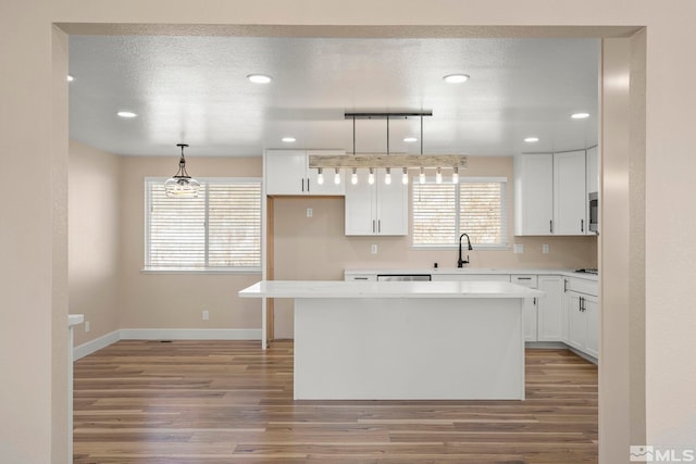 kitchen with a center island, white cabinets, and decorative light fixtures