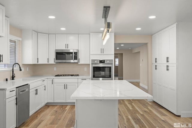 kitchen featuring a center island, white cabinets, stainless steel appliances, and light hardwood / wood-style floors