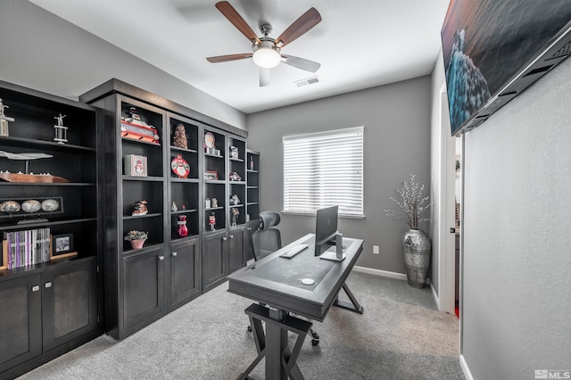 carpeted home office featuring ceiling fan