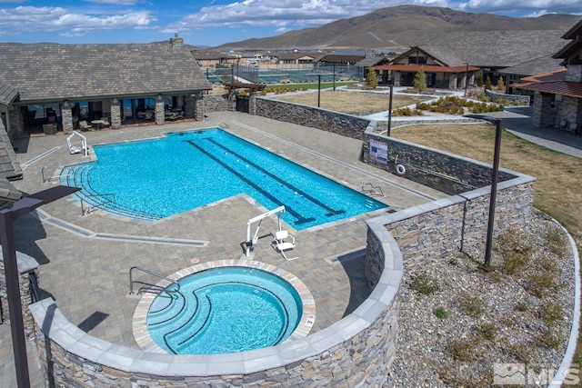 view of swimming pool featuring a mountain view, a patio area, and a hot tub